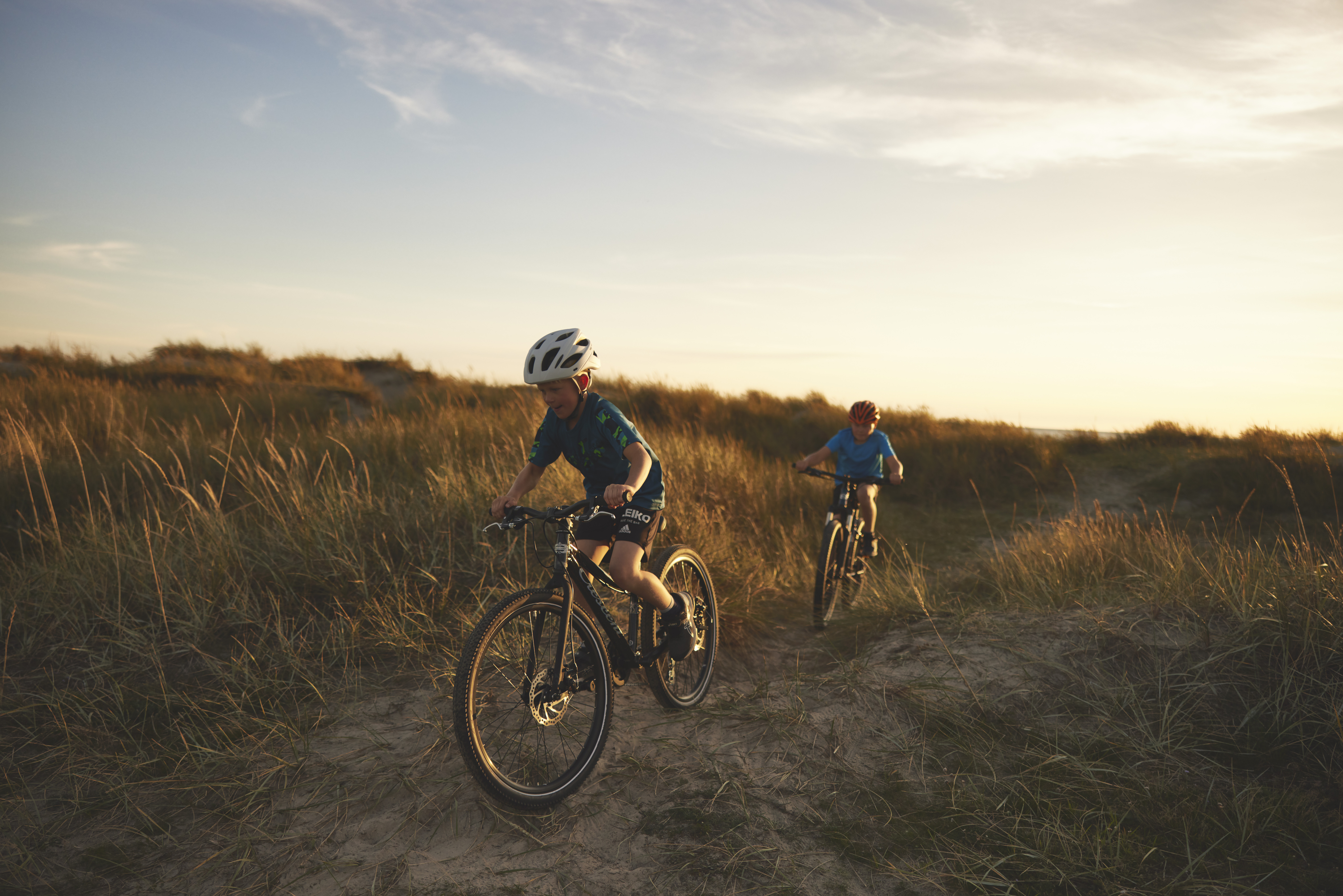 cyklande barn i solnedg&aring;ng